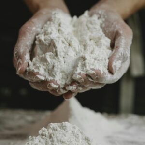 Close-up of a person holding a mound of flour in their hands inside a kitchen.