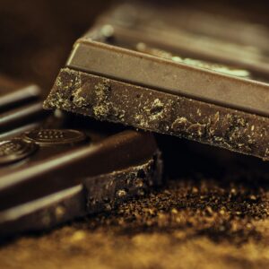 Macro shot of rich dark chocolate bars sprinkled with cocoa powder, highlighting texture and indulgence.